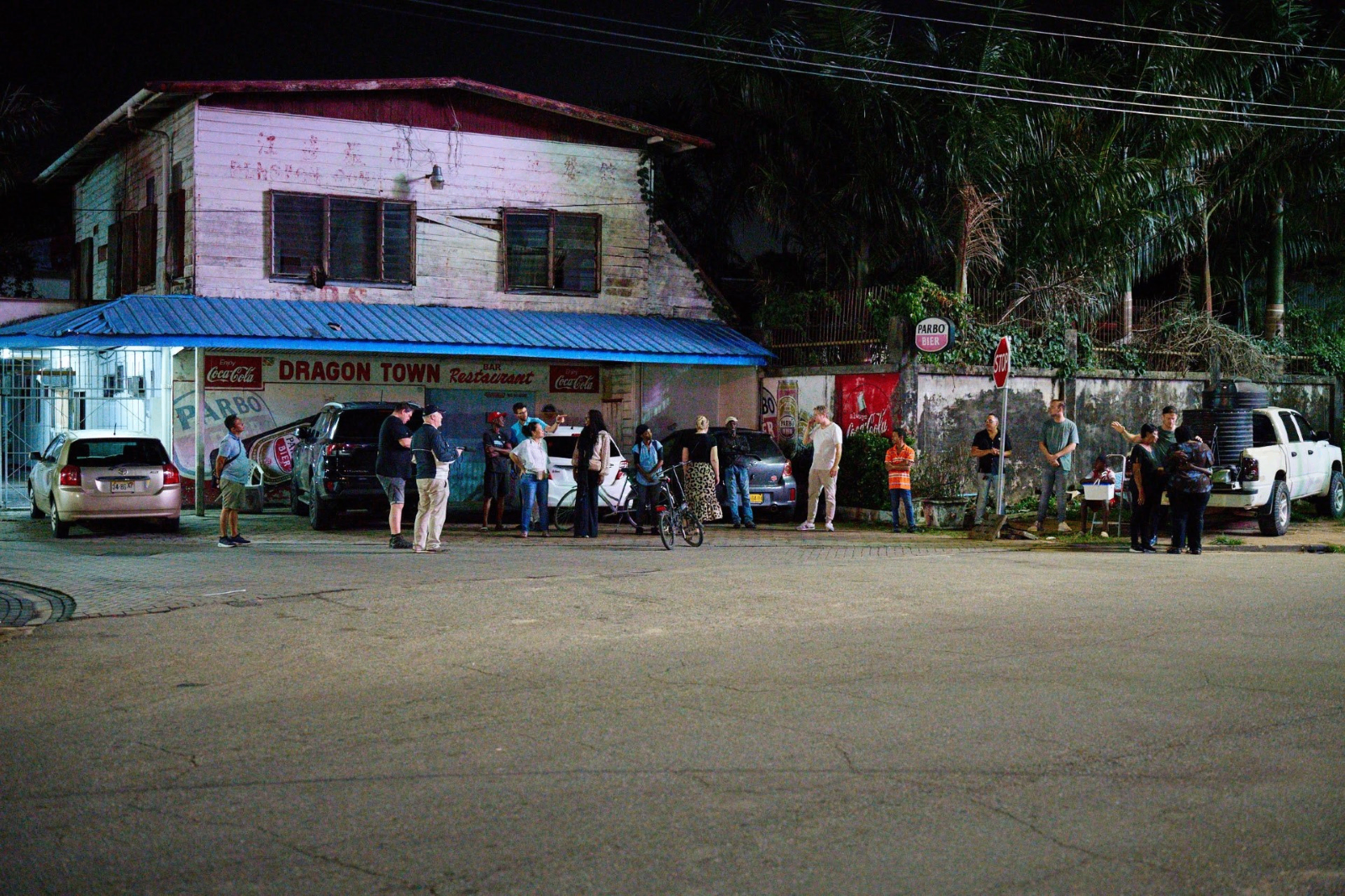 Groep evangelisten in gesprek met omstanders 's avonds op straat voor het Dragon Town Restaurant op Sommelsdijk in Paramaribo